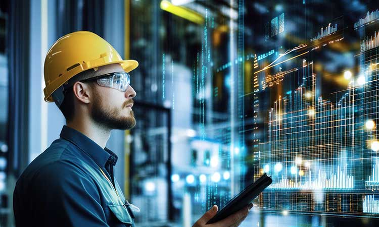 Male wearing hardhat inside manufacturing plan looking at data