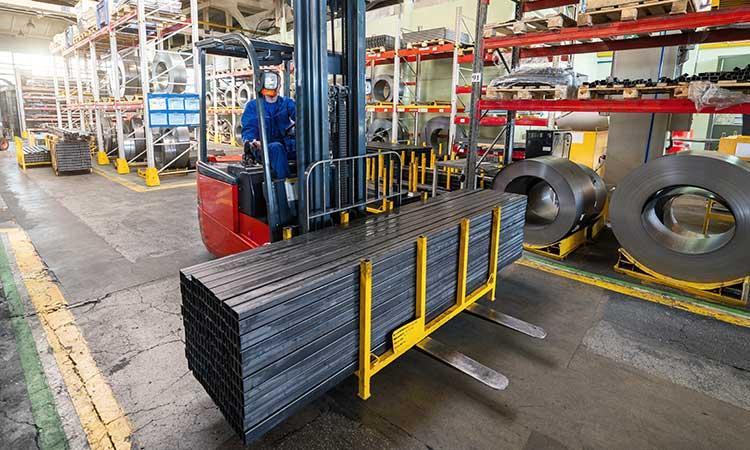 Forklift carrying steel bars within a manufacturing facility